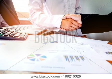 Two Business People Shaking Hands While Sitting At The Working Place