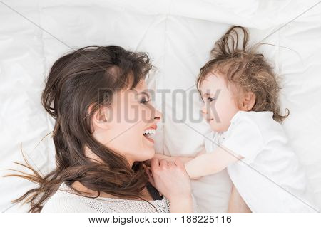 Young beautiful and smiling mother with baby girl. Daughter close to loving mom.