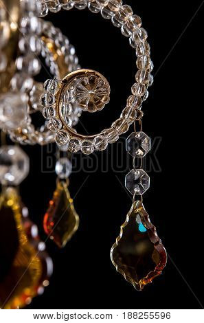 Classic Chandelier for interior decoration of the living room. Large chandelier close-up details decorated with crystals and amber isolated on black background. Gold modern a piece of interior for designers.