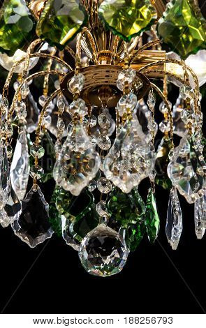 Chandelier for interior of the living room. chandelier details decorated with green crystals isolated on black background. Close-up photo