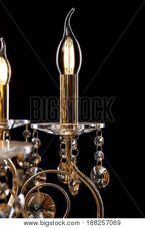 Classic Chandelier for interior decoration of the living room. Large chandelier close-up details decorated with crystals isolated on black background. Gold modern a piece of interior for designers.