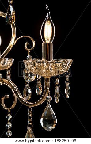 Classic Chandelier for interior decoration of the living room. Large chandelier close-up details decorated with crystals isolated on black background. Gold modern a piece of interior for designers.