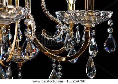 Classic Chandelier for interior decoration of the living room. Large chandelier close-up details decorated with crystals isolated on black background. Gold modern a piece of interior for designers.