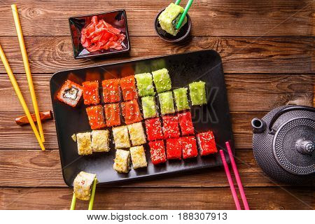 Sushi Set rolls with soy sauce served on black plate on wooden background