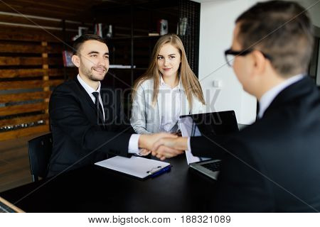 Sell Concept. Young Couple Greetings With Manager In Office.