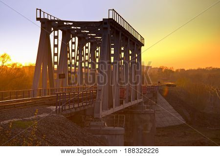 Railway Bridge Over The River At Sunset.
