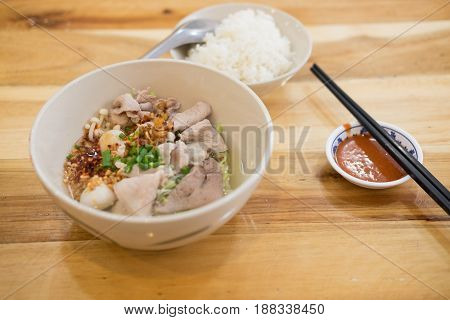 Thai fusion food noodle with pork and vegetable on wood table eating with rice