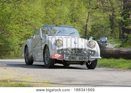 STOCKHOLM SWEDEN - MAY 22 2017: White Triumph Sport TR3A HT classic car from 1960 driving on a country road in the public race Gardesloppet in the forests at Djurgarden Stockholm Sweden. May 22 2017