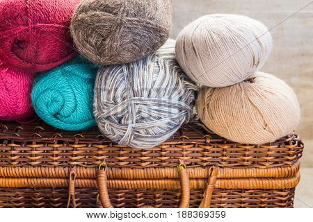 Vintage crafts wicker chest clews balls of multi-color wool yarn red blue white beige grey knitting hobby concept header banner for websites close up