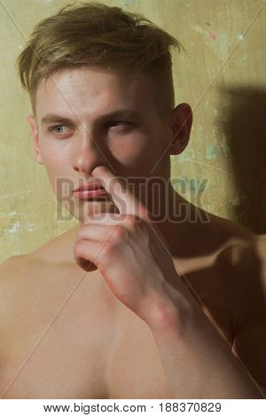 man or macho with naked muscle chest picking nose with finger on serious face on beige background. Antipathy and boredom