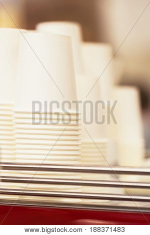 Rows of upside down white cups of cardboard, paper for beverages, disposable tableware for caffee, tee, abstract nonexistent logo. Coffee culture, coffe to go, fast food, service, catering concepts. Vertical