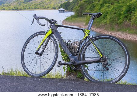 Cyclo cross bicycle with a helmet standing at the road near reservoir