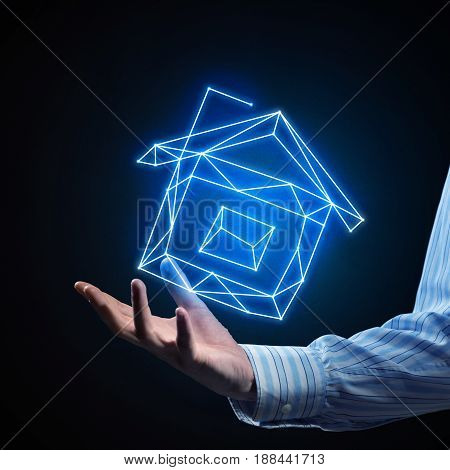 Close of buinessman holding in palm glowing house symbol