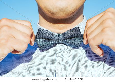 the man straightens a bowtie on his skirt