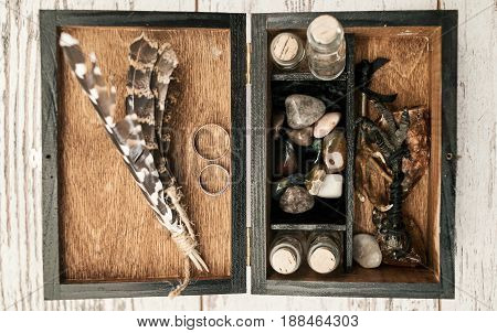 Wooden box with wedding rings bird's paws feathers empty bottles and stones on wooden background free space. Wedding decorations
