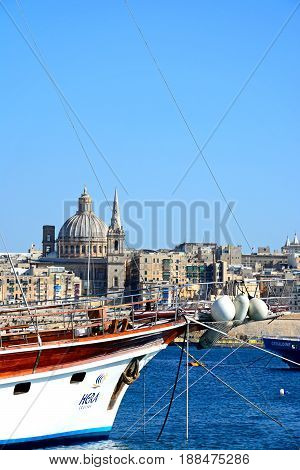 VALLETTA, MALTA - MARCH 30, 2017 - View of St Pauls Anglican Cathedral and the Basilica of Our Lady of Mount Carmel with a yacht in the foreground seen across the Grand Harbour from Sliema Valletta Malta Europe, March 30, 2017.