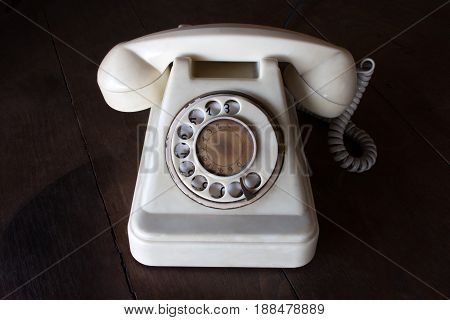 Old White Vintage Telephone, Phone Land  Or Landline With Dust, Circle Dialpad And Scratches On Wood