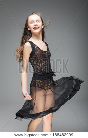 smiling cute young girl dancing. model is dressed in a black and leopard pattern dance dress. red lips. metal braces