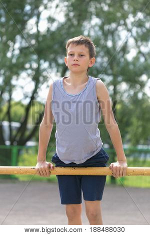 A Teenager In A T-shirt Is Engaged In Gymnastics On A Horizontal Bar