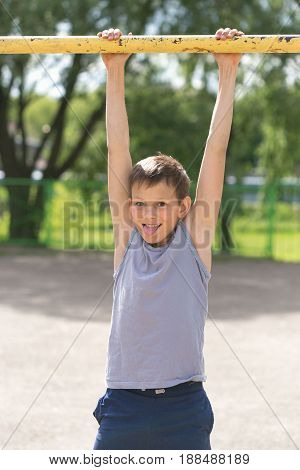 A Teenager In A T-shirt Is Engaged In Gymnastics On A Horizontal Bar
