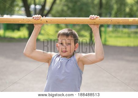A Teenager In A T-shirt Is Engaged In Gymnastics On A Horizontal Bar