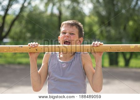 A Teenager In A T-shirt Is Engaged In Gymnastics On A Horizontal Bar