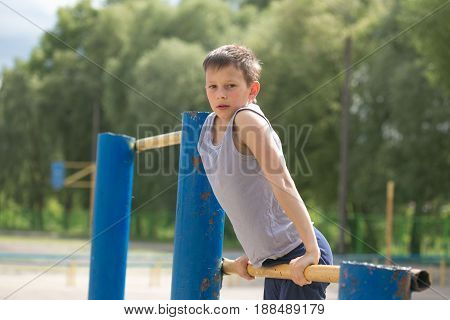 A Teenager In A T-shirt Is Engaged In Gymnastics On A Horizontal Bar
