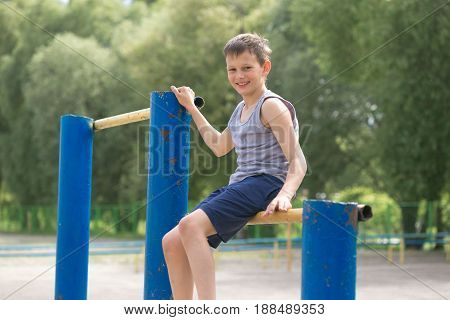 A Teenager In A T-shirt Is Engaged In Gymnastics On A Horizontal Bar