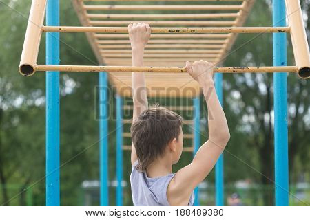 A Teenager In A T-shirt Is Engaged In Gymnastics On A Horizontal Bar