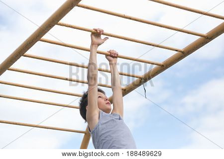A Teenager In A T-shirt Is Engaged In Gymnastics On A Horizontal Bar