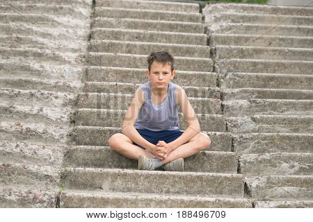 A Teenager In A T-shirt Sits On Concrete Steps