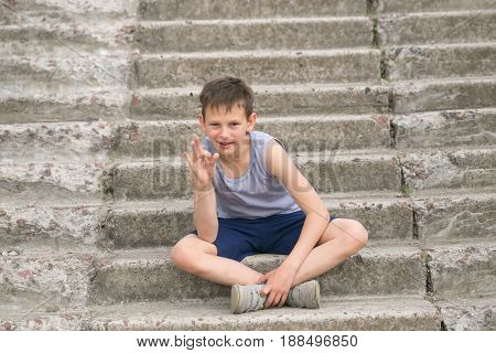 A Teenager In A T-shirt Sits On Concrete Steps
