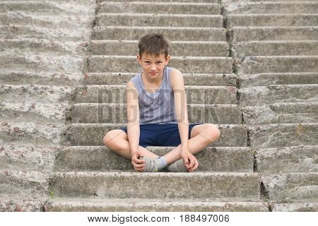 A Teenager In A T-shirt Sits On Concrete Steps