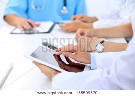 Group of doctors at medical meeting. Close up of physician using tablet computer