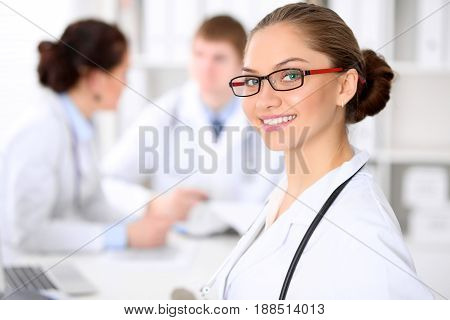 Happy doctor woman  with medical staff at the hospital sitting at the table and discussing medical history