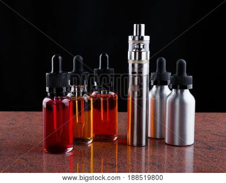 Electronic cigarette and bottles with assorted vape liquid on granite surface and black background