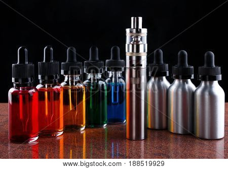 Electronic cigarette and bottles with assorted vape liquid on granite surface and black background