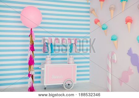 Children's zone with sweets: lollipops, ice cream, macarons, balloon and candy bar. Children room with blue stripe background.