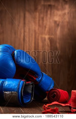 Boxing background with blue gloves and red bandage on wooden background. Pair of the boxing gloves. Colorful sportwear and accessories. Vertical photo. Energy, power and victory. Concept of the healthy lifestyle.