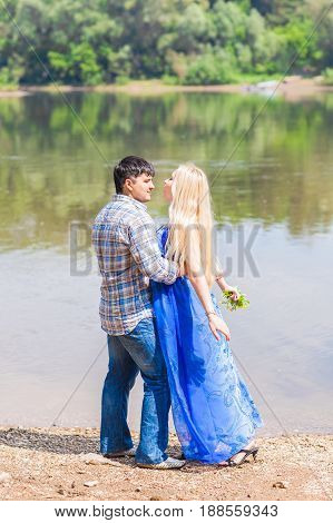 Young happy couple having fun beside river in summer sunny day
