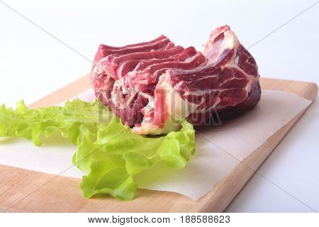 Raw beef edges and lettuce leaf on wooden desk isolated on white background from above and copy space. ready for cookin