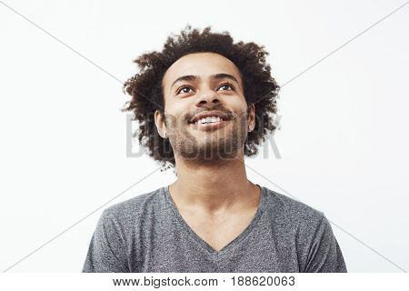 Happy african man smiling looking up over white background. Copy space.