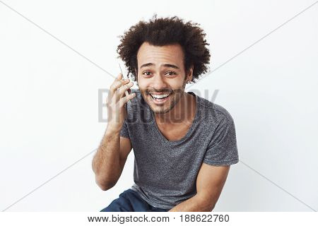 Handsome cheerful african man smiling speaking on phone over white background.