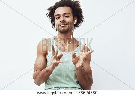 Young african man listening to music in headphones dancing over white background. Copy space.