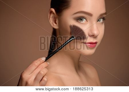 Beauty Girl with Makeup Brush. Bright Make-up for Brunette Woman with Beautiful Face. Perfect Skin. Applying Makeup