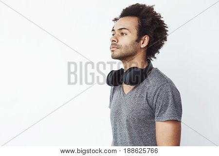 Portrait of young handsome african man with headphones over white background. Copy space.
