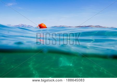 Marker buoy on surface of water. View half and half underwater.