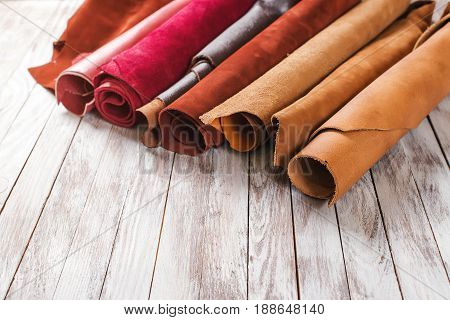 Multicolored Leather In Rolls On Wooden Background.