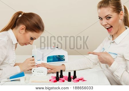 Relaxing time and wellness day concept. Blonde elegant woman visiting professional manicurist salon. Beautician makes perfect nails to client.