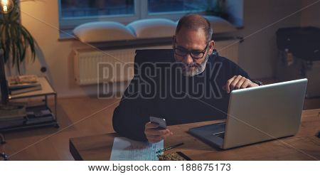 Mature businessman calculating finance on his laptop computer. Horizontal shot